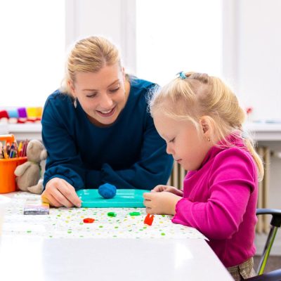 Female health care worker watching as a young girl plays with playdough