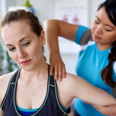 female physiotherapist with her hands on a female patient's shoulder.