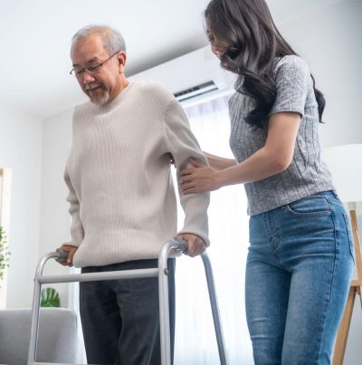 woman helping a senior man walk with a walker